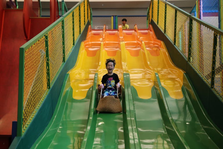 A cheerful child sliding down a colorful slide in an indoor playground, showcasing fun and excitement.