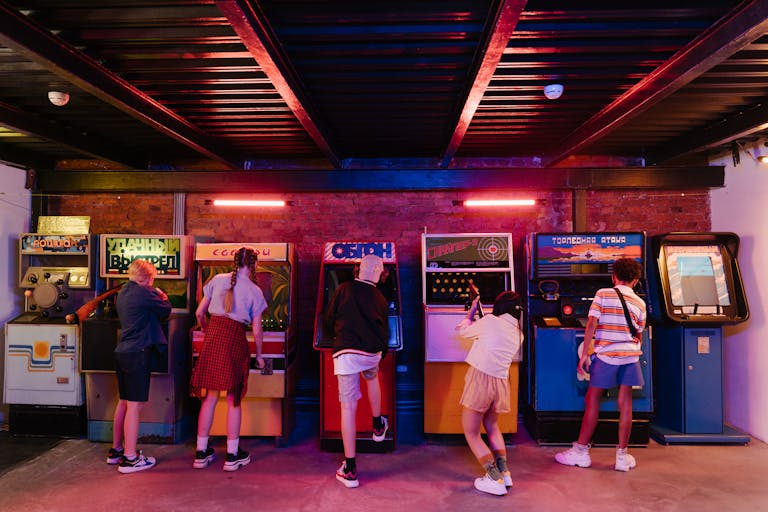 Group of teenagers playing various retro arcade games, enjoying a nostalgic gaming experience.