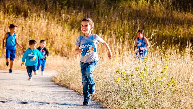 Children joyfully running in a park during a cheerful outdoor race event.